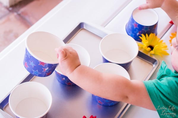 child taking stack of cups apart and laying out on a baking pan