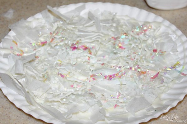 Paper plate with winter decorations like marsmallows, tissue paper and glitter.