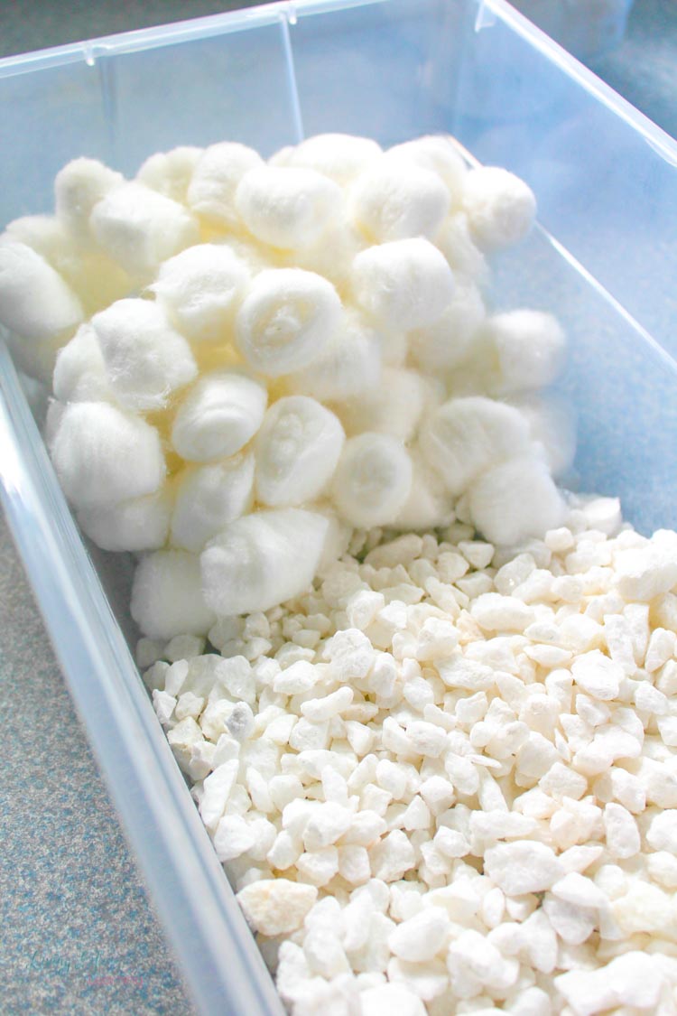 White cotton balls and white gravel stones in sensory bin