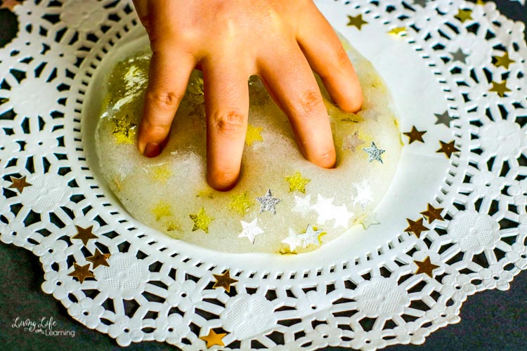 A child's hand playing with magical star slime
