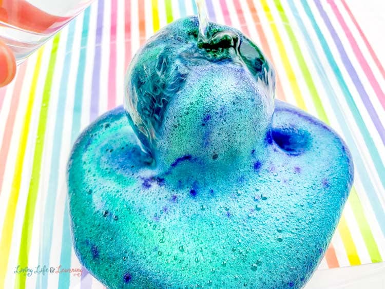 Blue fizzy ooze coming out of this fun apple volcano science experiment.