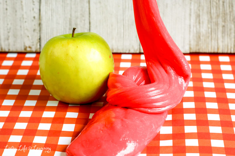 Red apple-scented slime recipe  on a red checked table next to a green apple for fall decor and activity