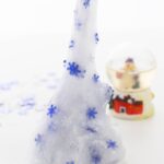 The snow globe is to the right behind the slime with snowflake confetti that is being stretched upwards. The text is placed at the bottom of the image saying "winter slime recipe"
