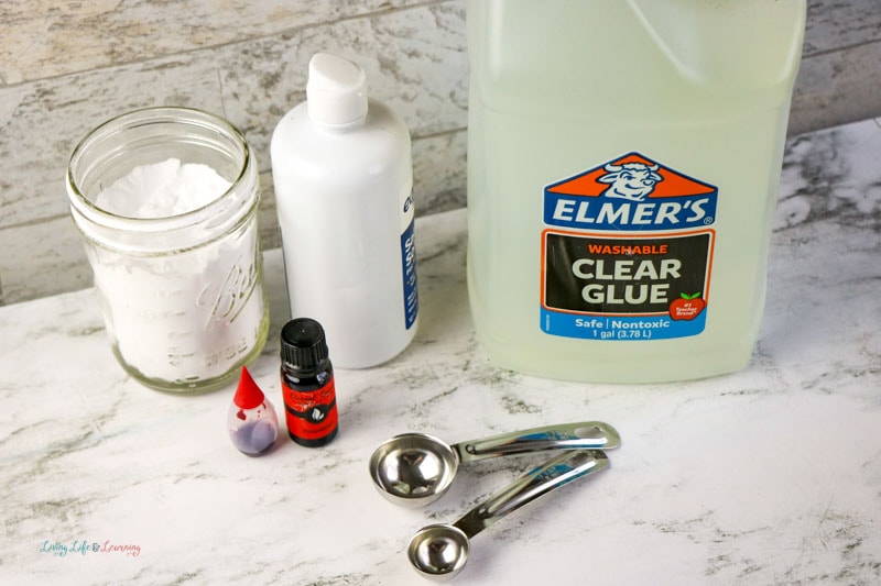 Supplies like Elmer's clear glue, contact solution, food coloring and an essential oil for Strawberry Slime Recipe