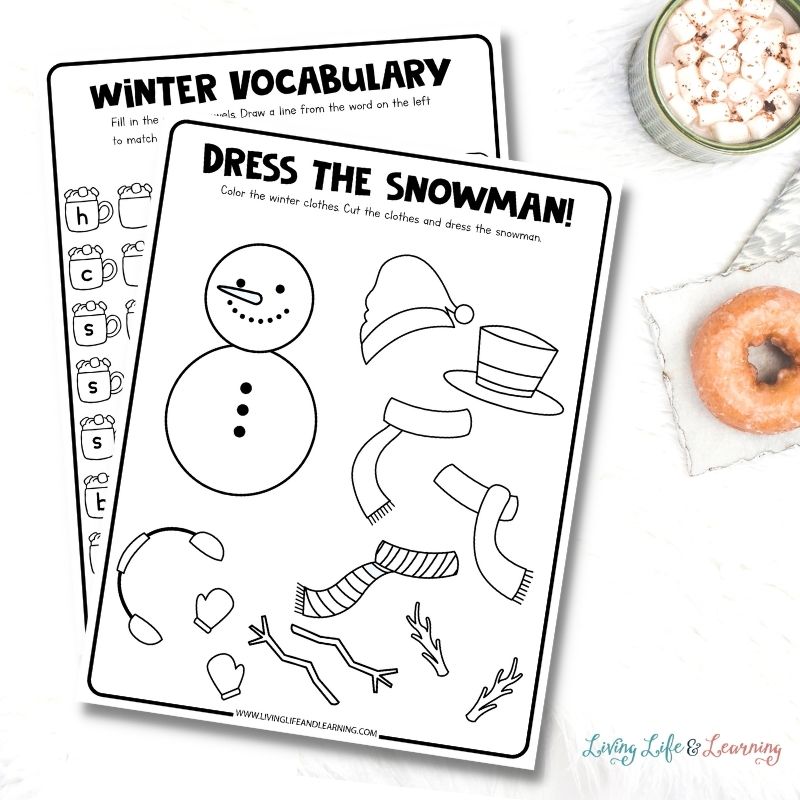 worksheets about dressing the snowman and winter vocabulary placed on a desk next to a cup of hot chocolate and a doughnut