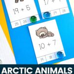There are three arctic animal addition cards on top of the blue-colored paper which also has a yellow-colored paper beneath it.