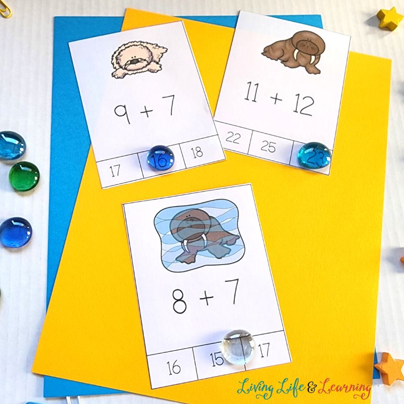 There are three arctic animal addition cards placed on top of the yellow-colored paper which also has a blue-colored paper beneath it.