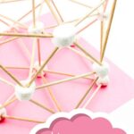 There are marshmallows connected together by toothpicks creating a structure that is placed on pink paper. This is the Hexagon Marshmallow STEM Building Challenge
