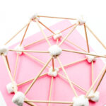 There are marshmallows connected together by toothpicks creating a structure that is placed on pink paper. This is the Hexagon Marshmallow STEM Building Challenge