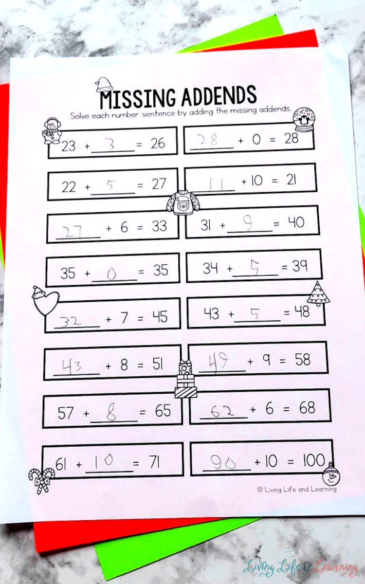 A Christmas Addition Worksheet about missing addends on a table with red and green cardstock behind it